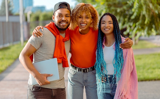 A group of three teenagers is smiling, all wearing braces